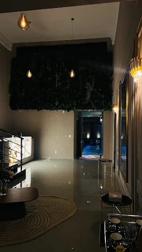 Corredor com jardim vertical e pendentes âmbar à noite