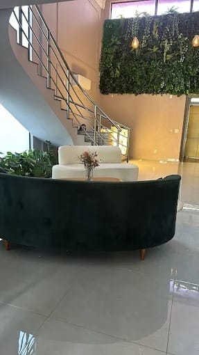 Lounge com sofá curvo de veludo verde e poltrona off-white