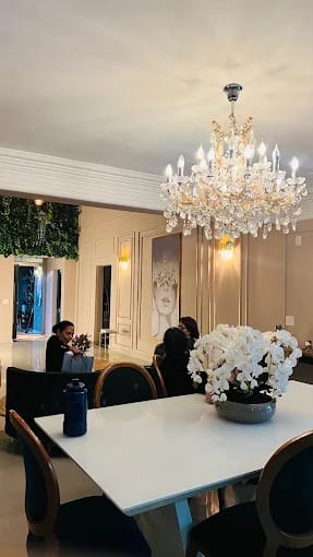 Sala com lustre de cristal, mesa branca e orquídeas